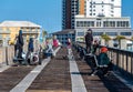 A number of Asian people fish from the pier on blue sunny sky day