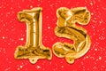 The number of the balloon made of golden foil, the number fifteen on a red background with sequins.