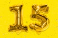 The number of the balloon made of golden foil, the number fifteen on a yellow background with sequins.