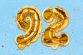 The number of the balloon made of golden foil, the number ninety-two on a blue background with sequins. Royalty Free Stock Photo