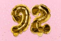 The number of the balloon made of golden foil, the number ninety-two on a pink background with sequins. Royalty Free Stock Photo