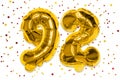 The number of the balloon made of golden foil, the number ninety-two on a white background with multicolored sequins Royalty Free Stock Photo