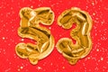 The number of the balloon made of golden foil, the number fifty-three on a red background with sequins.