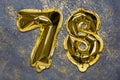 The number of the balloon made of golden foil, the number seventy-eight on a gray background with sequins.