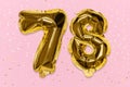 The number of the balloon made of golden foil, the number seventy-eight on a pink background with sequins.