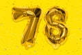 The number of the balloon made of golden foil, the number seventy-eight on a yellow background with sequins.