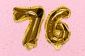 The number of the balloon made of golden foil, the number seventy-six on a pink background with sequins.