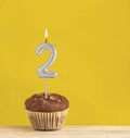 Number 2 birthday candle - Chocolate cupcake on a yellow background Royalty Free Stock Photo