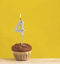 Number 4 birthday candle - Chocolate cupcake on a yellow background Royalty Free Stock Photo