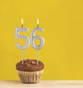 Number 56 birthday candle - Chocolate cupcake on a yellow background Royalty Free Stock Photo