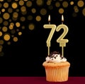 Number 72 birthday candle - Cupcake on black background with out of focus lights