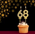 Number 68 birthday candle - Cupcake on black background with out of focus lights