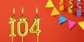 Number 104 birthday candle on an orange background with pennants Royalty Free Stock Photo