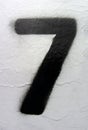 Number 7 black sprayed digit on rust painted white metal surface