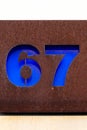 Number 67 blue cutout house number on metal plate