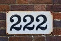 Number 222 on brown brick wall, black numerals