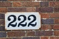 Number 222 on brown brick wall, black numerals