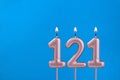 Number 121 - Burning anniversary candle on blue foamy background