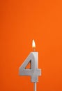 Number 4 - Burning anniversary candle on orange foamy background