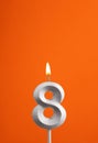 Number 8 - Burning anniversary candle on orange foamy background