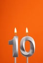 Number 10 - Burning anniversary candle on orange foamy background