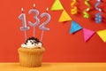 Birthday cupcake with number 132 candle - Sparkling orange background with bunting Royalty Free Stock Photo