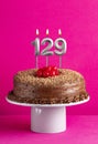 Number 129 candle - Chocolate cake on pink background Royalty Free Stock Photo