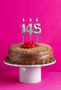Number 145 candle - Chocolate cake on pink background