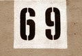 Number 69 on cement wall in stencil in brown tone