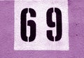 Number 69 on cement wall in stencil in purple tone