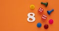Number 8 with dice and board game pieces - Orange eva rubber background Royalty Free Stock Photo