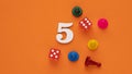 Number five in white with pieces and gambling dice - Orange eva rubber background Royalty Free Stock Photo