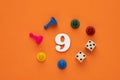 Number 9 with dice and board game pieces - Orange eva rubber background Royalty Free Stock Photo