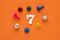 Number 7 with dice and board game pieces - Orange eva rubber background Royalty Free Stock Photo