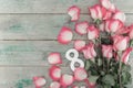 Number eight as symbol of a holiday 8 march in a frame of pink roses on rustic wooden background. Greeting card with flowers for