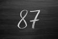 Number eighty seven enumeration written with a chalk on the blackboard