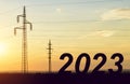 The number 2023 with electric pylons at sunset.