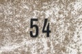 The Number 54, fifty four, on a surface with lichen