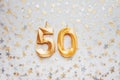 Number 50 fifty golden celebration birthday candle on Festive Background.