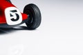 Number five painted in front of a retro old racing toy car with black wheels on a white background close up still Royalty Free Stock Photo