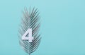 Number four shape with silver palm leaves on blue background. Summer concept. Flat lay. Top view