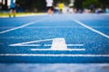 Number four on the start of a running track .Blue treadmill with different numbers and white lines.Selective focus on Number.