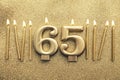 Number 65 gold celebration candle on a glitter background