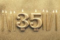 Number 35 gold celebration candle on a glitter background