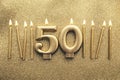 Number 50 gold celebration candle on a glitter background Royalty Free Stock Photo