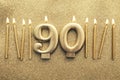 Number 90 gold celebration candle on a glitter background Royalty Free Stock Photo