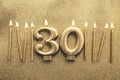 Number 30 gold celebration candle on a glitter background Royalty Free Stock Photo