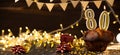 Number 80 golden festive burning candles in a cake, wooden holiday background. Eighty years since the birth. the concept