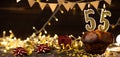 Number 55 golden festive burning candles in a cake, wooden holiday background. fifty-five years since the birth. the Royalty Free Stock Photo