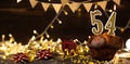 Number 54 golden festive burning candles in a cake, wooden holiday background. fifty-four years since the birth. the Royalty Free Stock Photo